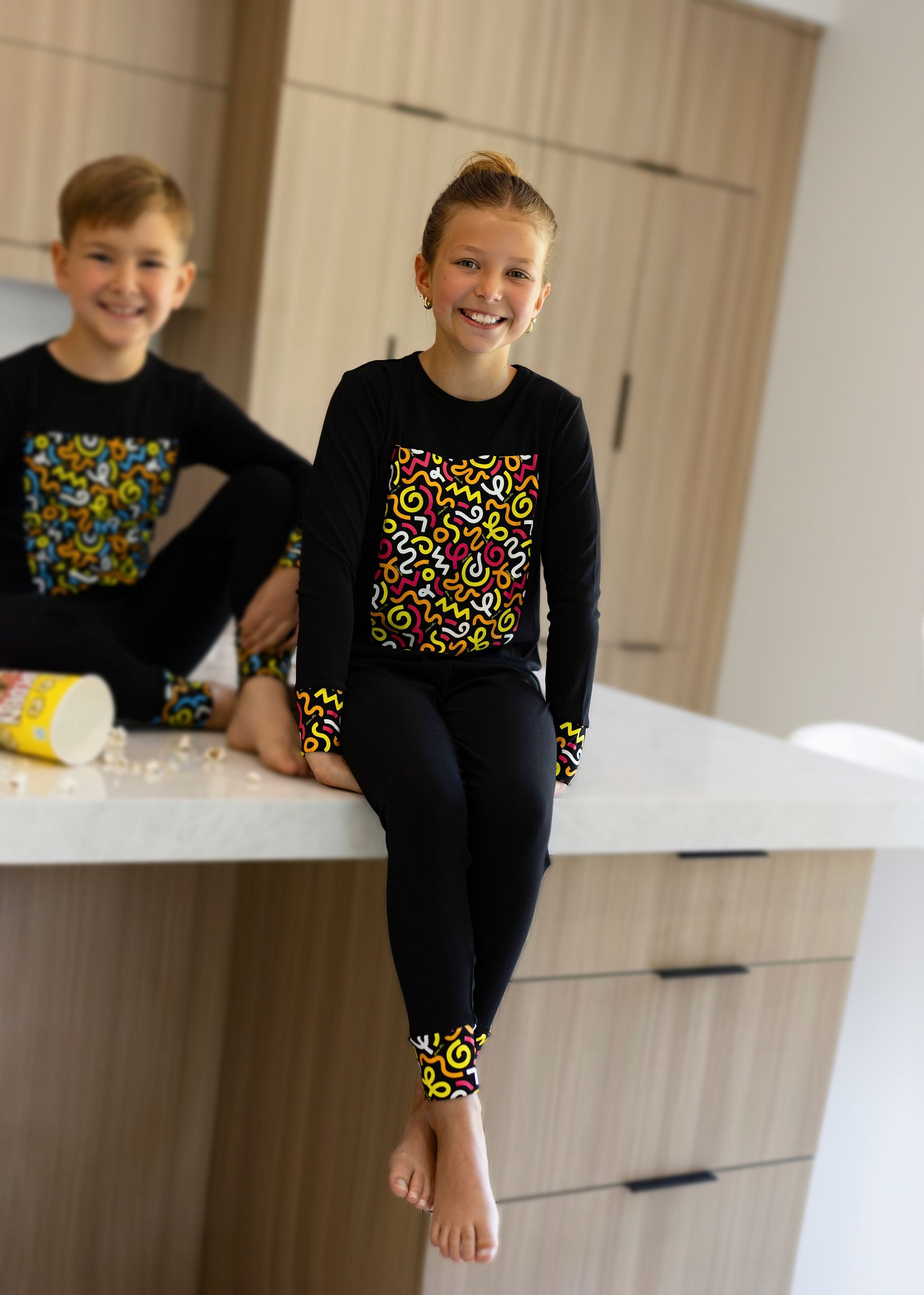 Child in Dottie Lou Brush Pop black pajamas with colorful doodle print — solo child model photo 9