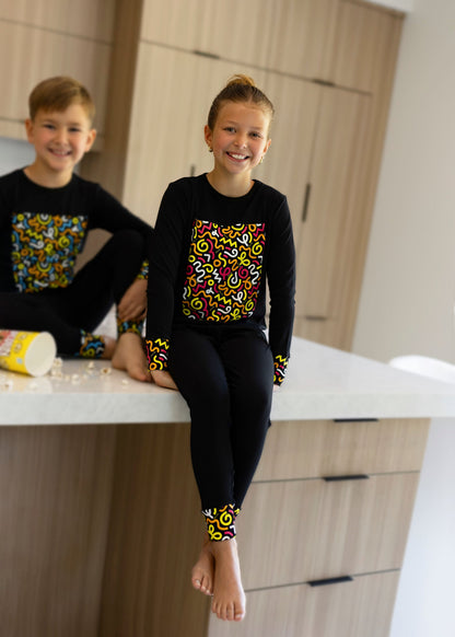 Child in Dottie Lou Brush Pop black pajamas with colorful doodle print — solo child model photo 9
