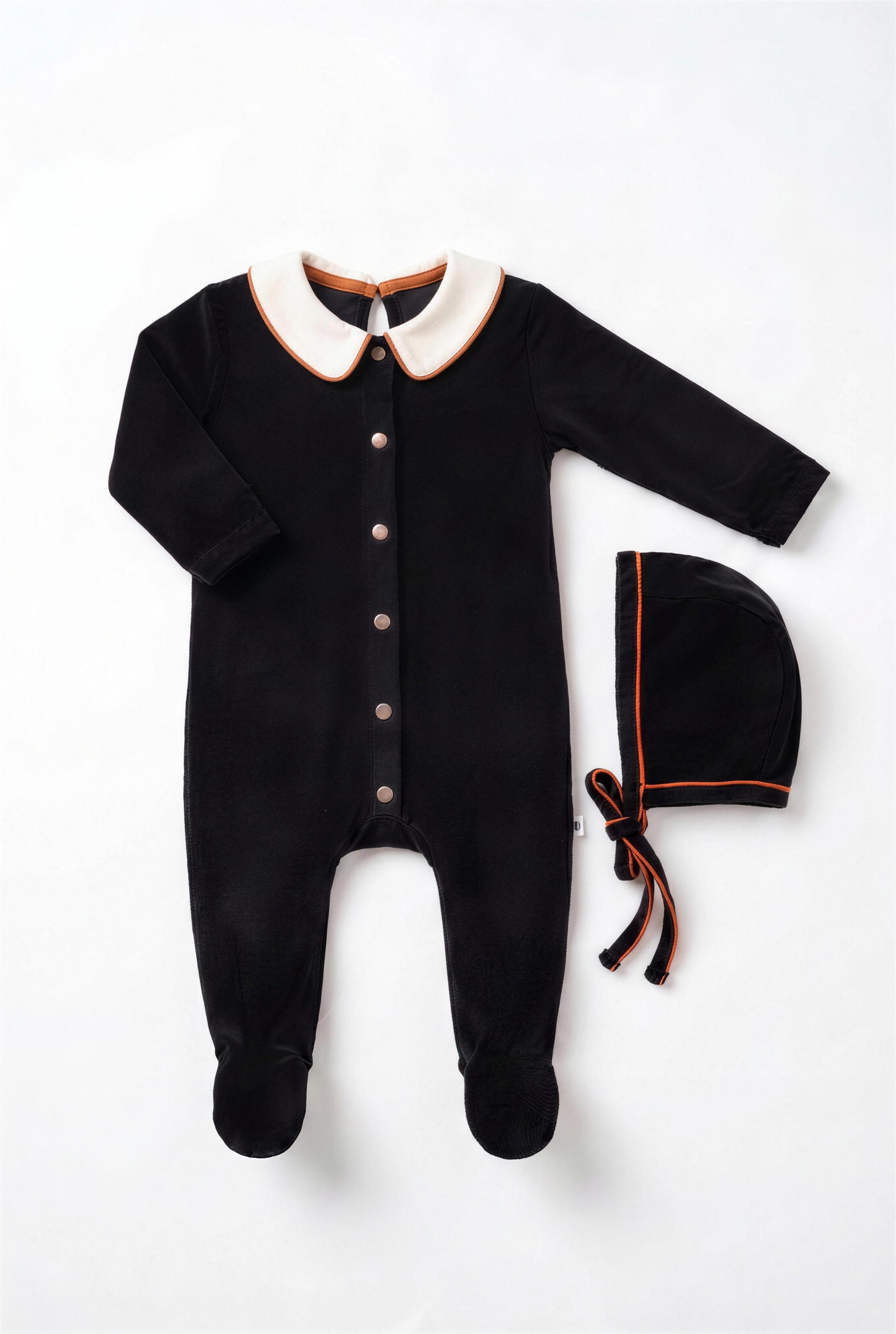 Dottie Lou Classic Noir boys baby footie pajama with matching hat, black velour with ivory collar and orange piping — flatlay