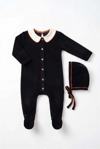 Dottie Lou Classic Noir boys baby footie pajama with matching hat, black velour with ivory collar and orange piping — flatlay
