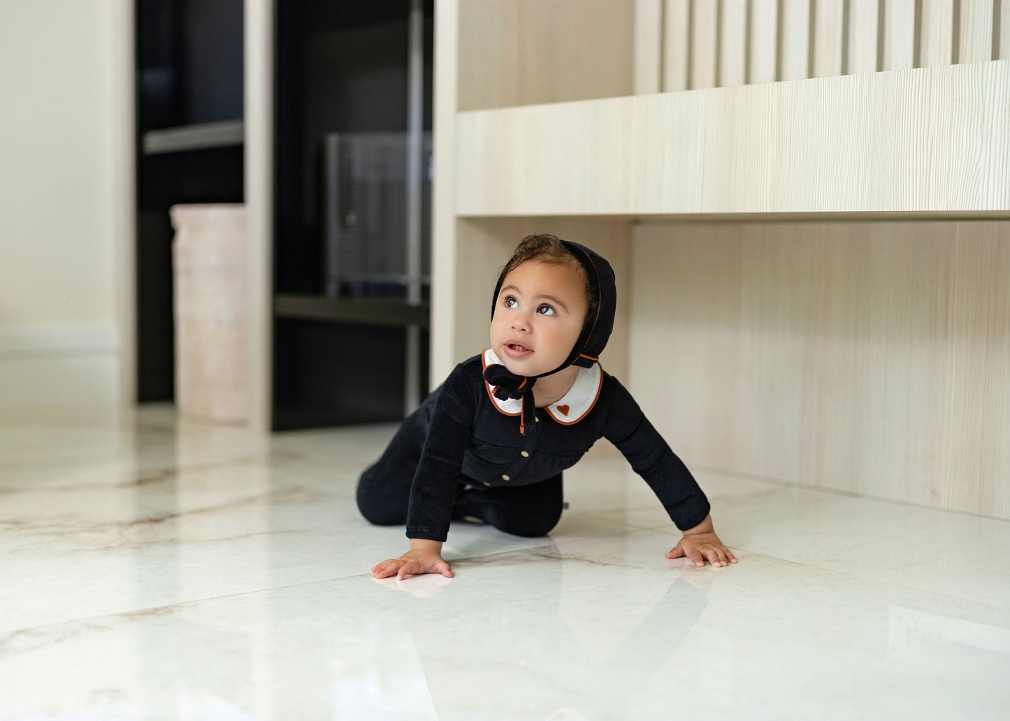 Child wearing Dottie Lou Classic Noir black velour loungewear with ivory Peter Pan collar and orange piping — solo child model photo 1
