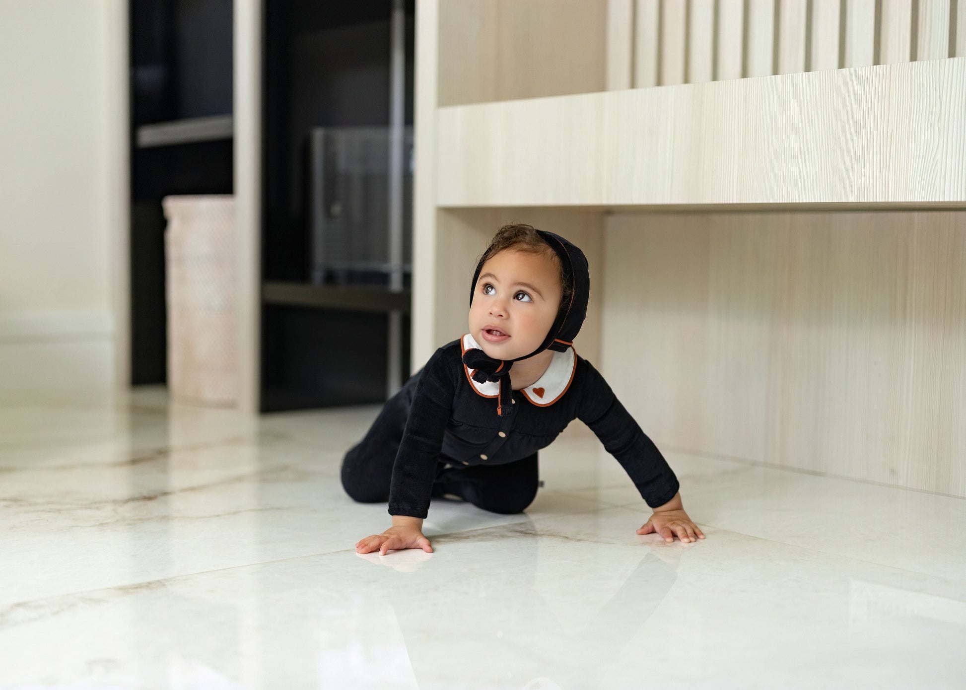Child wearing Dottie Lou Classic Noir black velour loungewear with ivory Peter Pan collar and orange piping — solo child model photo 1