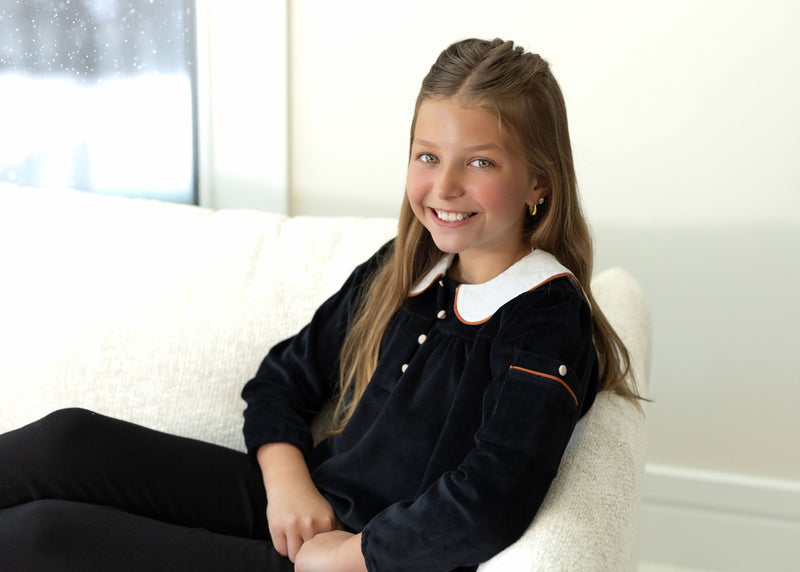Child wearing Dottie Lou Classic Noir black velour loungewear with ivory Peter Pan collar and orange piping — solo child model photo 12