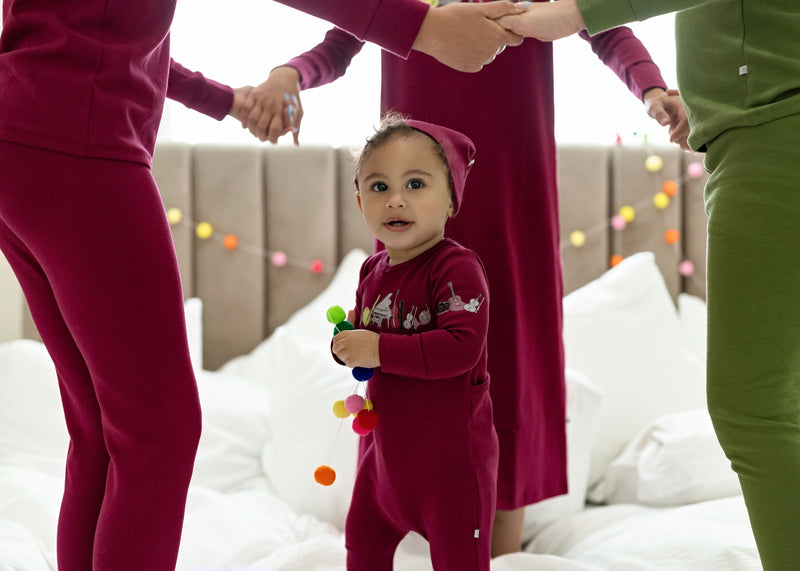 Baby girl wearing Dottie Lou Melody berry footie pajama with matching hat and music print